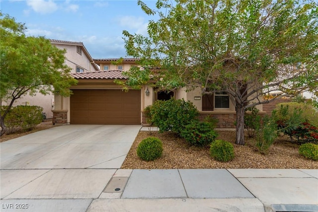 mediterranean / spanish-style house with a tile roof, stucco siding, concrete driveway, a garage, and stone siding