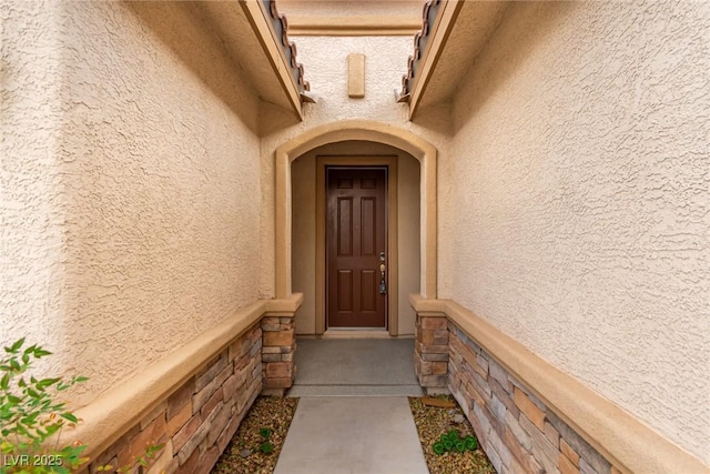 property entrance featuring stone siding and stucco siding