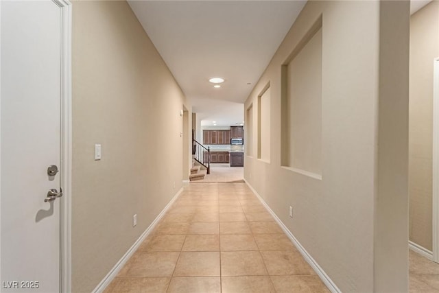 hall with stairway, light tile patterned flooring, and baseboards