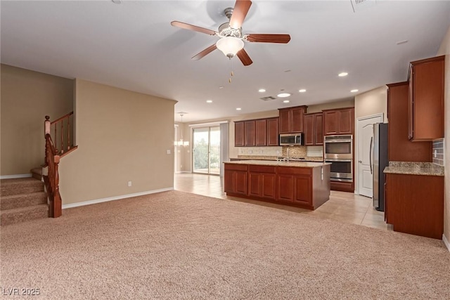 kitchen featuring light carpet, appliances with stainless steel finishes, open floor plan, and light countertops