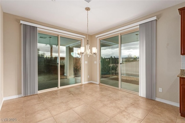 spare room with a wealth of natural light, baseboards, and a notable chandelier