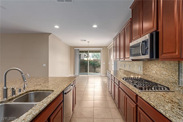 kitchen with pendant lighting, stainless steel appliances, tasteful backsplash, light tile patterned flooring, and a sink