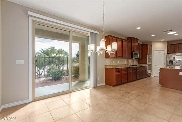 kitchen with baseboards, hanging light fixtures, appliances with stainless steel finishes, and decorative backsplash