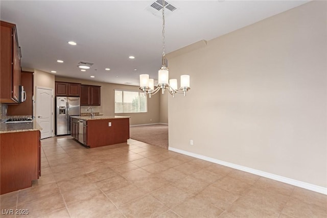 kitchen with a kitchen island with sink, stainless steel appliances, a sink, baseboards, and an inviting chandelier