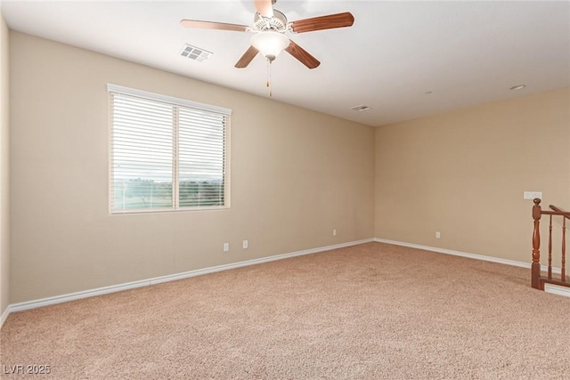 spare room with carpet floors, baseboards, visible vents, and a ceiling fan