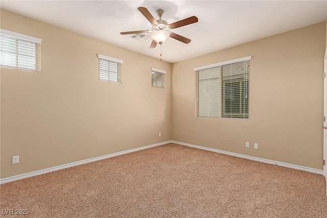 carpeted spare room with visible vents, a ceiling fan, a wealth of natural light, and baseboards