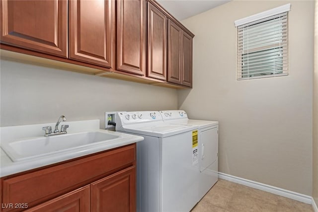 washroom with light tile patterned floors, a sink, baseboards, washer and dryer, and cabinet space