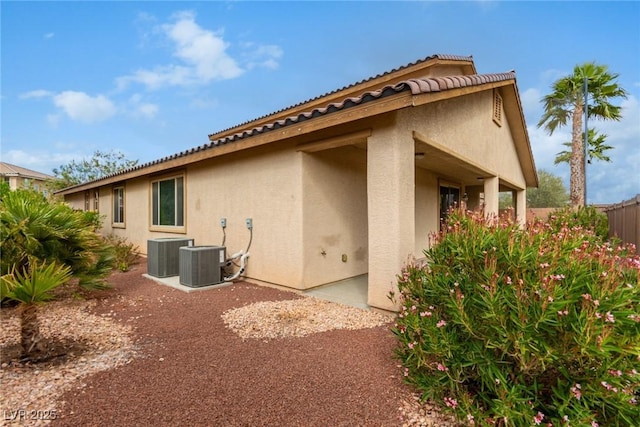 view of side of property featuring central AC, fence, and stucco siding