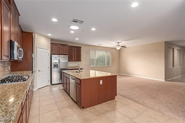 kitchen featuring light colored carpet, stainless steel appliances, a sink, visible vents, and open floor plan