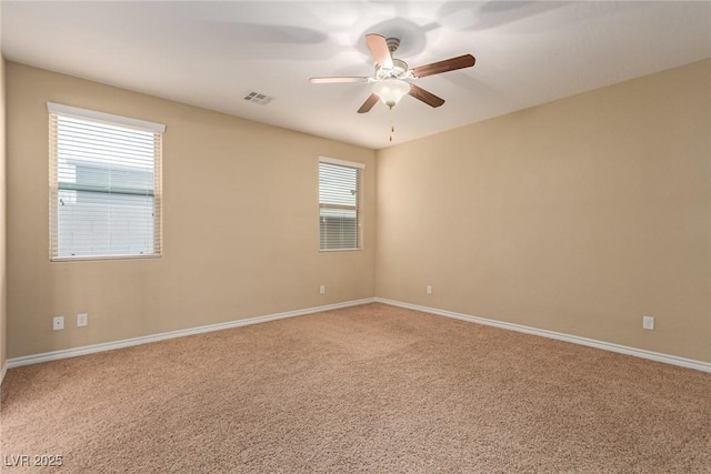 empty room featuring carpet, visible vents, ceiling fan, and baseboards