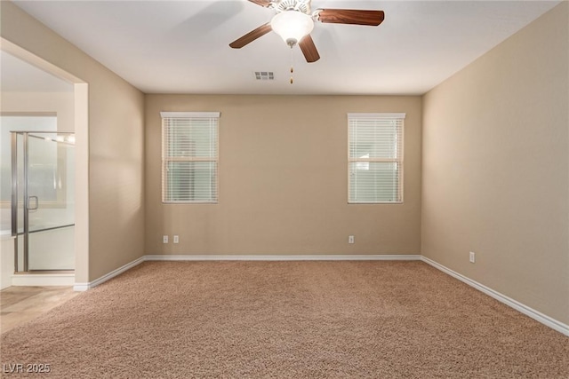 carpeted empty room featuring baseboards, visible vents, and a ceiling fan