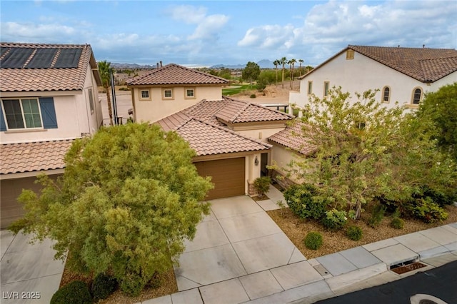 mediterranean / spanish house featuring a tile roof, stucco siding, concrete driveway, a garage, and a residential view