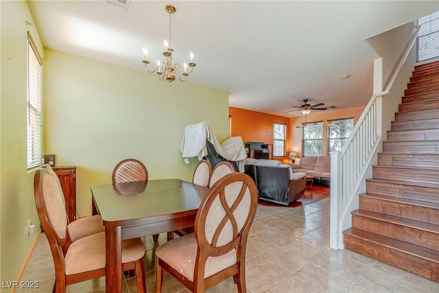 tiled dining area featuring ceiling fan with notable chandelier