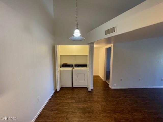 hallway with washing machine and dryer, dark hardwood / wood-style floors, and a high ceiling