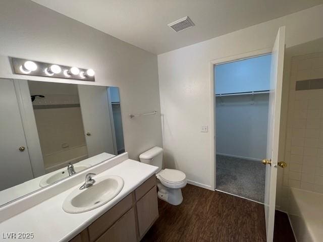 full bathroom with tiled shower / bath, vanity, toilet, and hardwood / wood-style floors