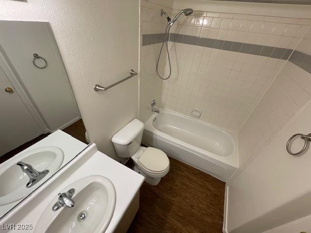 full bathroom with sink, tiled shower / bath combo, wood-type flooring, and toilet