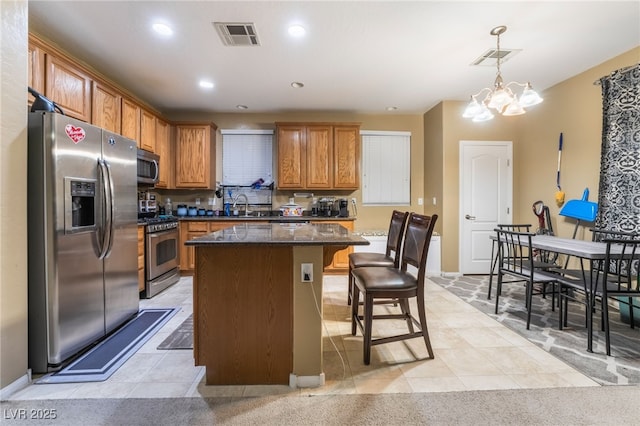 kitchen featuring a kitchen bar, sink, a kitchen island, pendant lighting, and stainless steel appliances