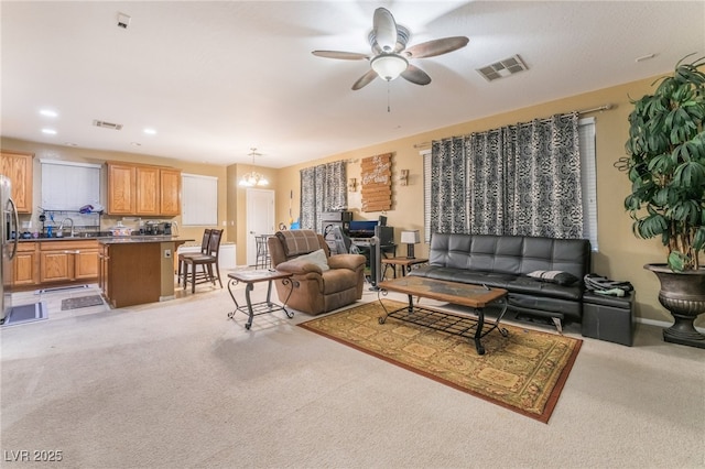 living room with ceiling fan with notable chandelier, sink, and light carpet