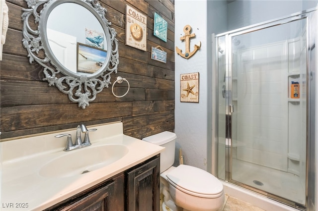 bathroom featuring vanity, a shower with shower door, wooden walls, and toilet