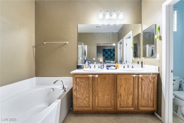 bathroom with vanity, tiled bath, and toilet