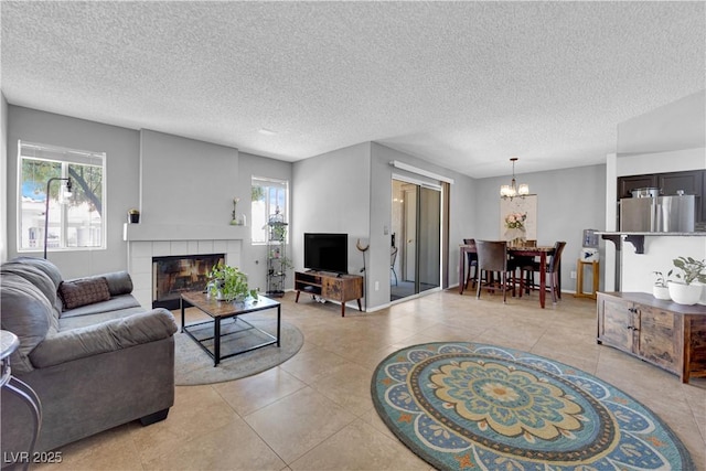 tiled living room with a tiled fireplace, a textured ceiling, and an inviting chandelier