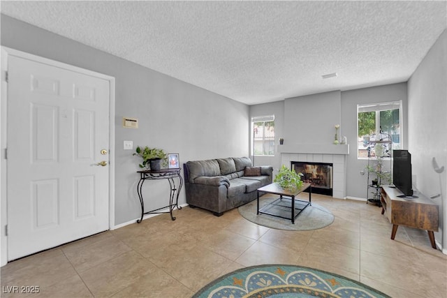 living room with light tile patterned floors, a tile fireplace, and a textured ceiling