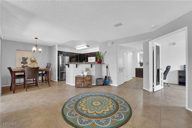 living room featuring light tile patterned floors, a textured ceiling, and an inviting chandelier