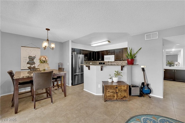 tiled dining area with a textured ceiling and a chandelier