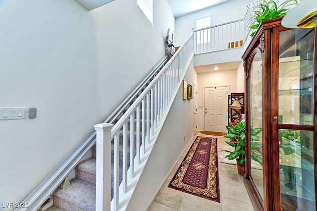 stairway with tile patterned flooring and a towering ceiling