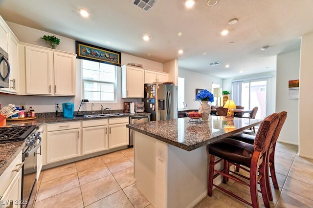 kitchen featuring a kitchen island, appliances with stainless steel finishes, sink, and dark stone counters