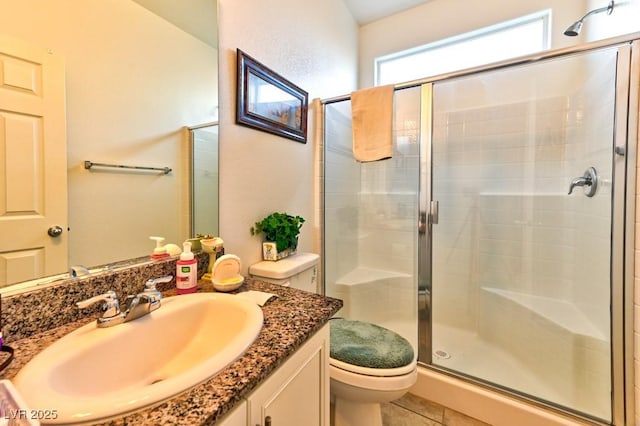 bathroom featuring tile patterned flooring, walk in shower, vanity, and toilet