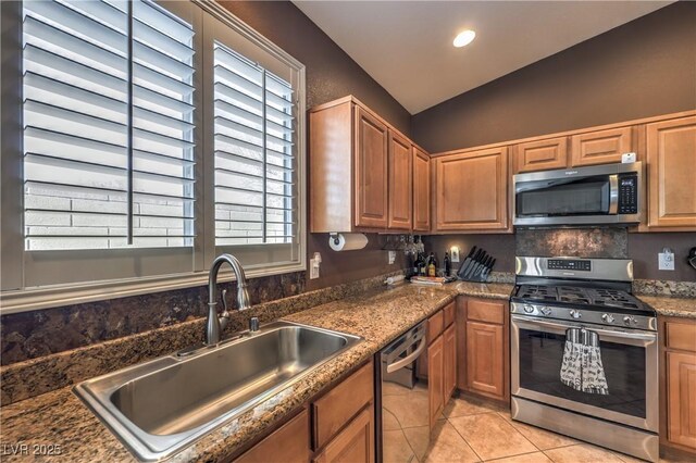 kitchen with lofted ceiling, sink, backsplash, light tile patterned floors, and stainless steel appliances