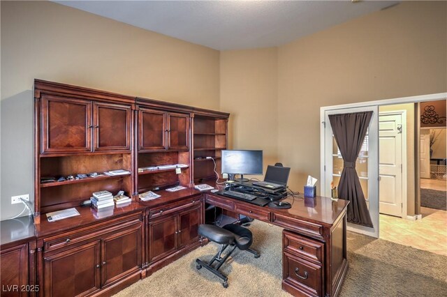 office area with vaulted ceiling and light carpet