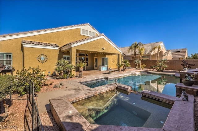 rear view of property with a pool with hot tub and a patio