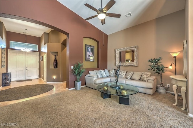 carpeted living room featuring ceiling fan with notable chandelier and high vaulted ceiling