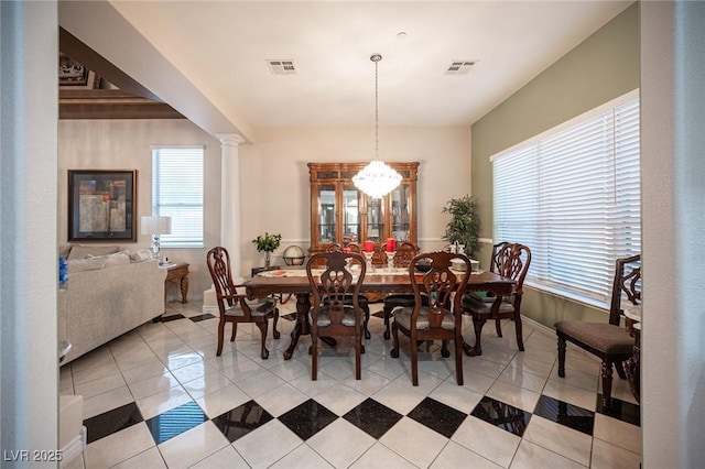 dining room featuring a notable chandelier, decorative columns, and light tile patterned floors