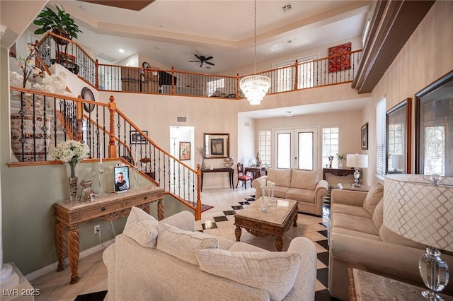 tiled living room with a notable chandelier, a raised ceiling, and a high ceiling