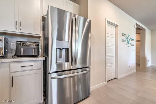 kitchen with white cabinetry, light hardwood / wood-style floors, stainless steel fridge with ice dispenser, and backsplash