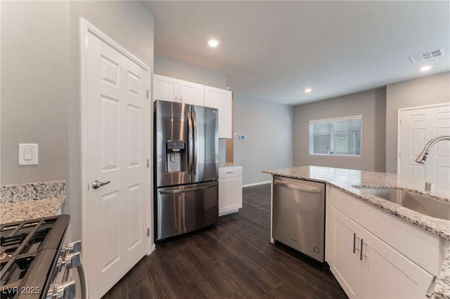 kitchen with stainless steel appliances, light stone countertops, sink, and white cabinets