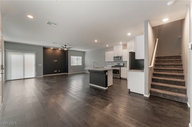 kitchen with white cabinetry, appliances with stainless steel finishes, dark wood-type flooring, and a center island with sink