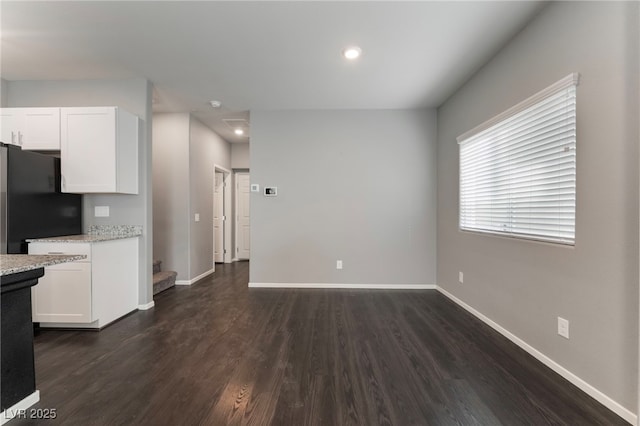 kitchen with black fridge, white cabinetry, dark hardwood / wood-style flooring, and light stone countertops