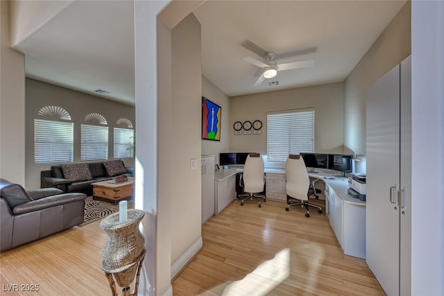 home office featuring built in desk, ceiling fan, and light wood-type flooring