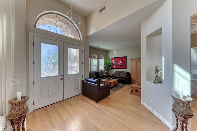 entryway with a notable chandelier, light wood-type flooring, and french doors