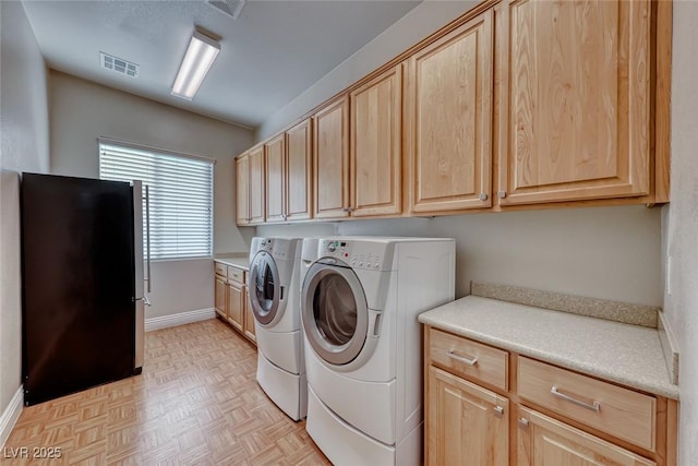 washroom featuring light parquet floors, cabinets, and washing machine and clothes dryer