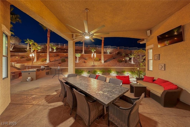 patio at night with an outdoor living space and ceiling fan