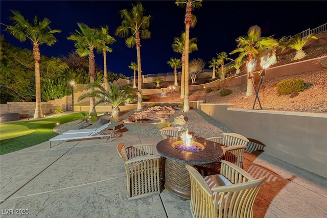 patio at night featuring an outdoor fire pit