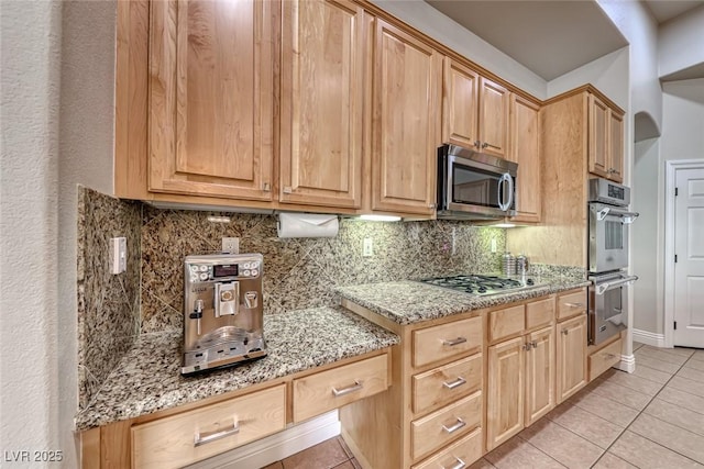 kitchen with light stone counters, light tile patterned floors, tasteful backsplash, and appliances with stainless steel finishes