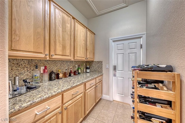 kitchen with tasteful backsplash, light stone countertops, light tile patterned floors, and light brown cabinetry