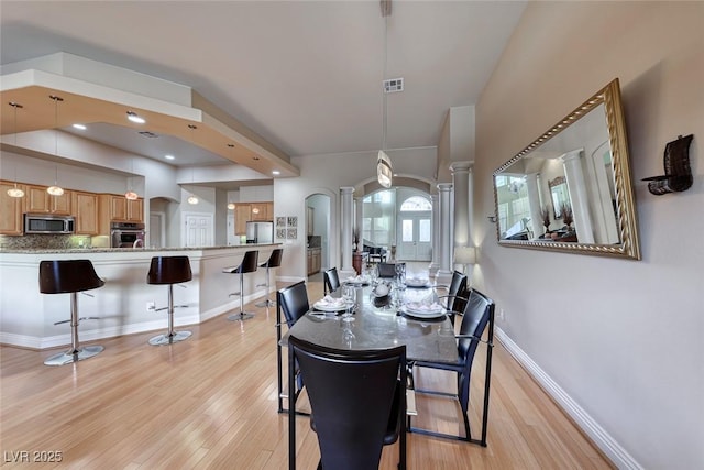 dining area with light wood-type flooring and ornate columns