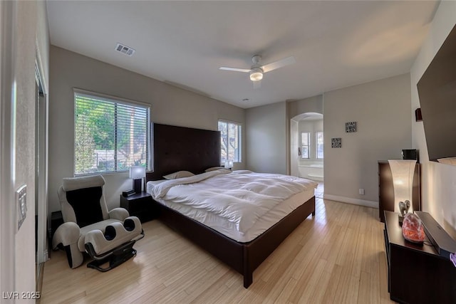 bedroom featuring ceiling fan, light hardwood / wood-style floors, and ensuite bath